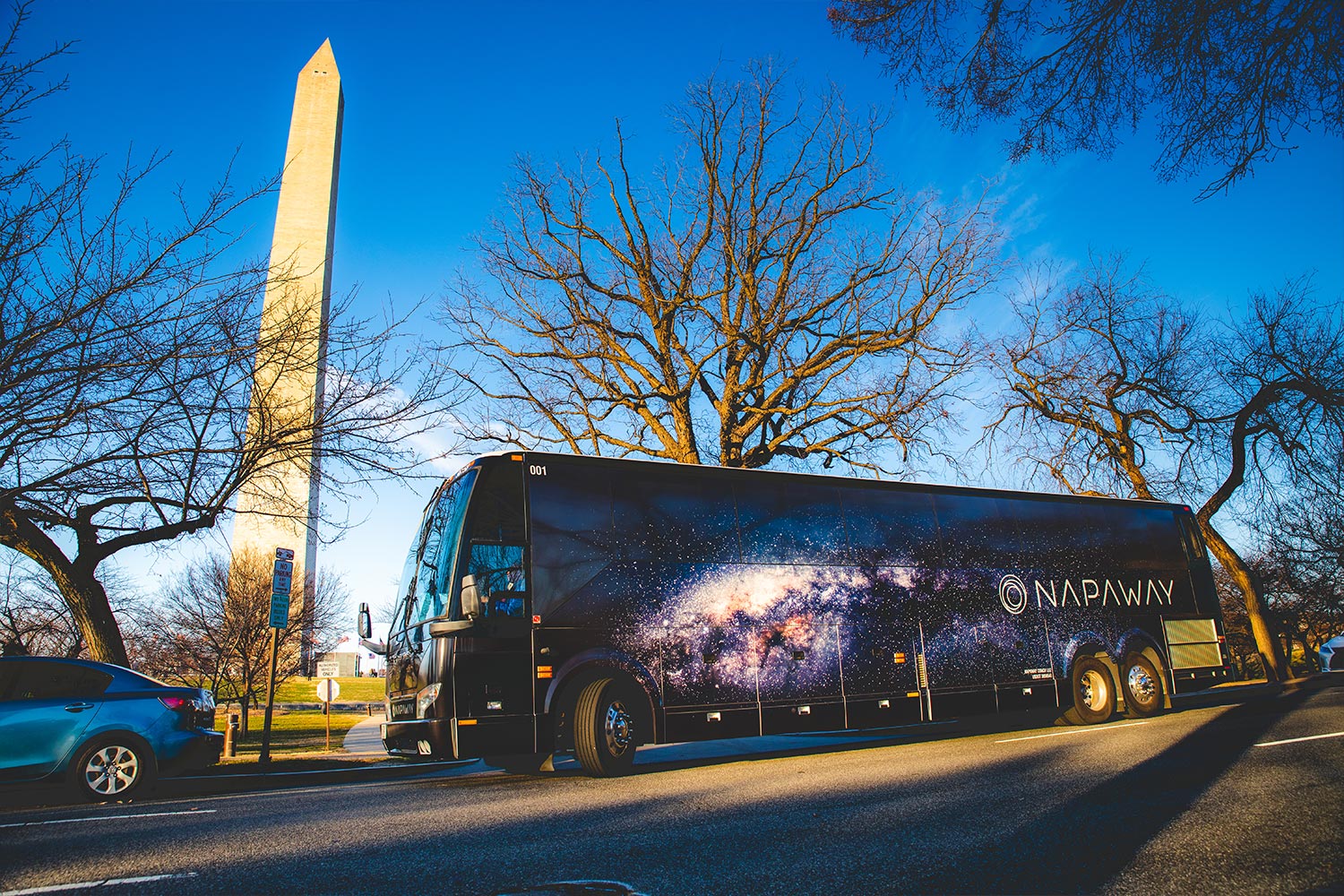A Napaway sleeper bus driving in front of the Washington Monument in D.C.